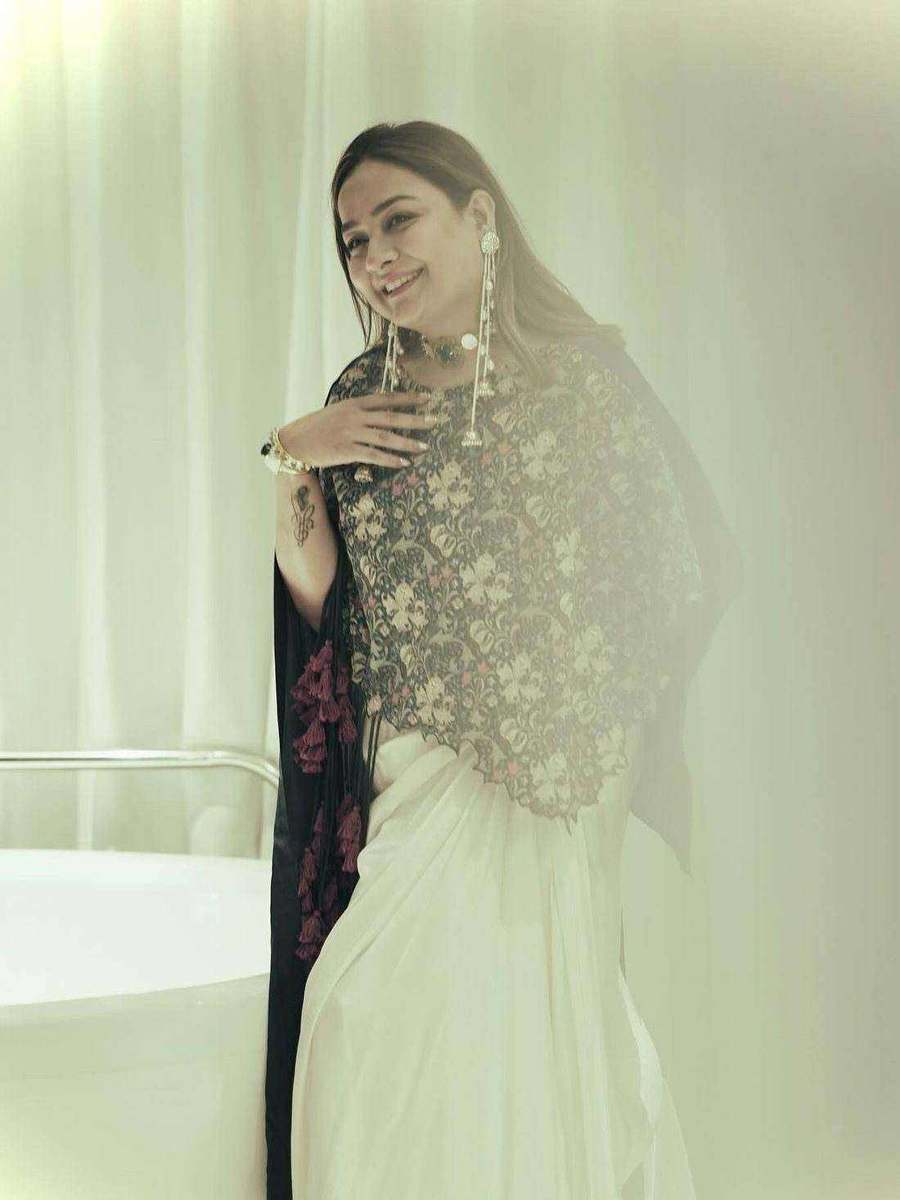 A styling client of Tanya Jain in the same look, the cape drawn across the shoulders against a pale curtain