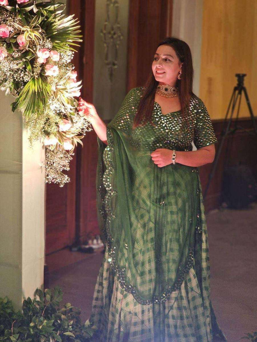 A green mirror-work lehenga beside a floral arrangement