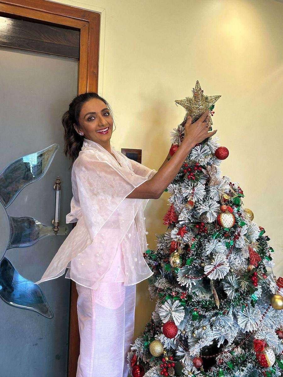 Shanthi Priya, styled by Tanya Jain in an ivory organza jacket and trousers, reaching up to a Christmas tree